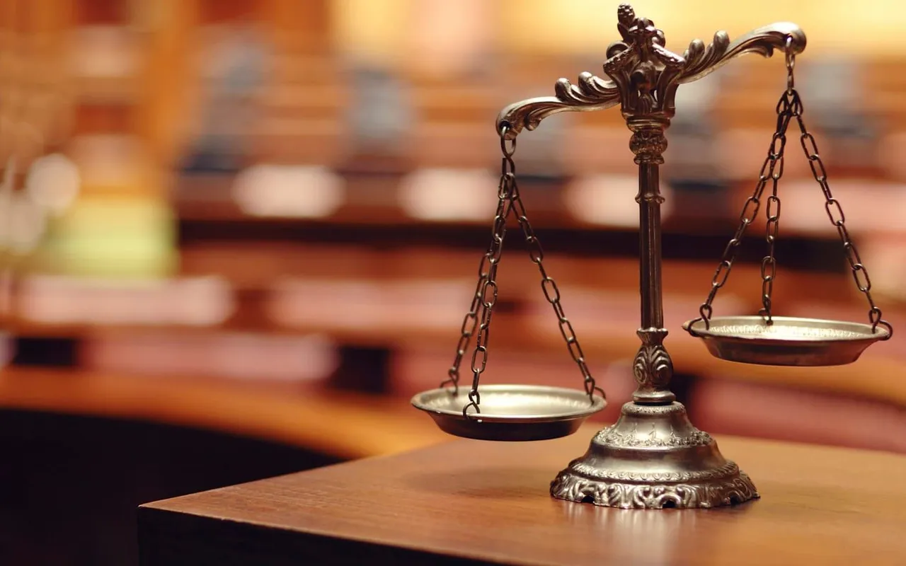Brass justice scales on a wooden table symbolizing legal battles between billionaire families